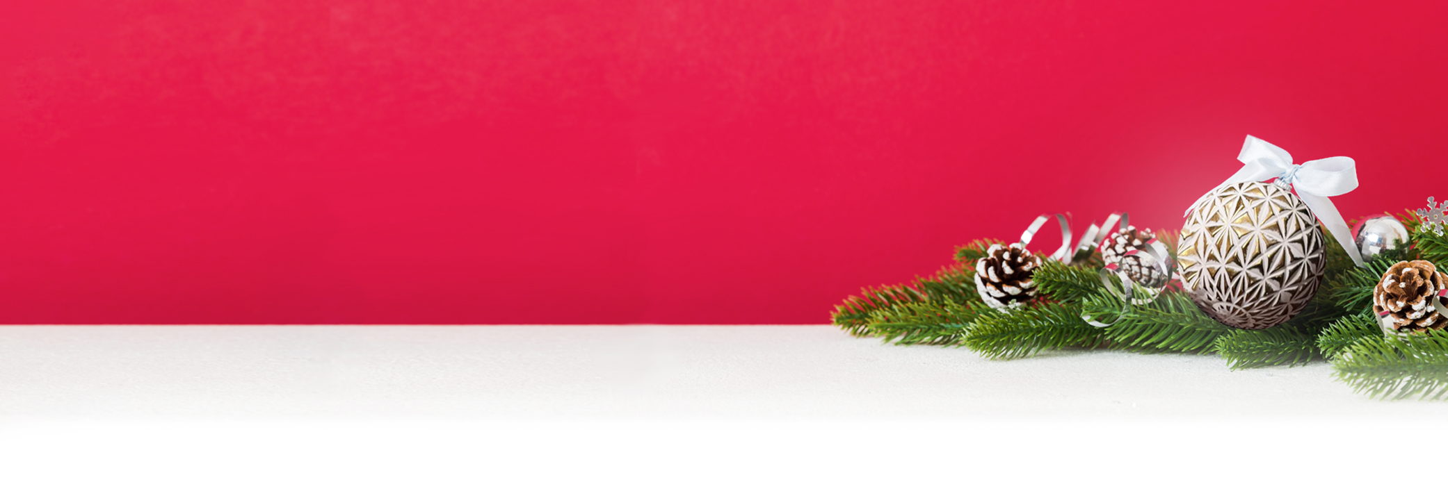Ein festlich geschmückter Tisch mit Tannenzweigen, Kiefernzapfen und verziertem Ei vor rotem Hintergrund